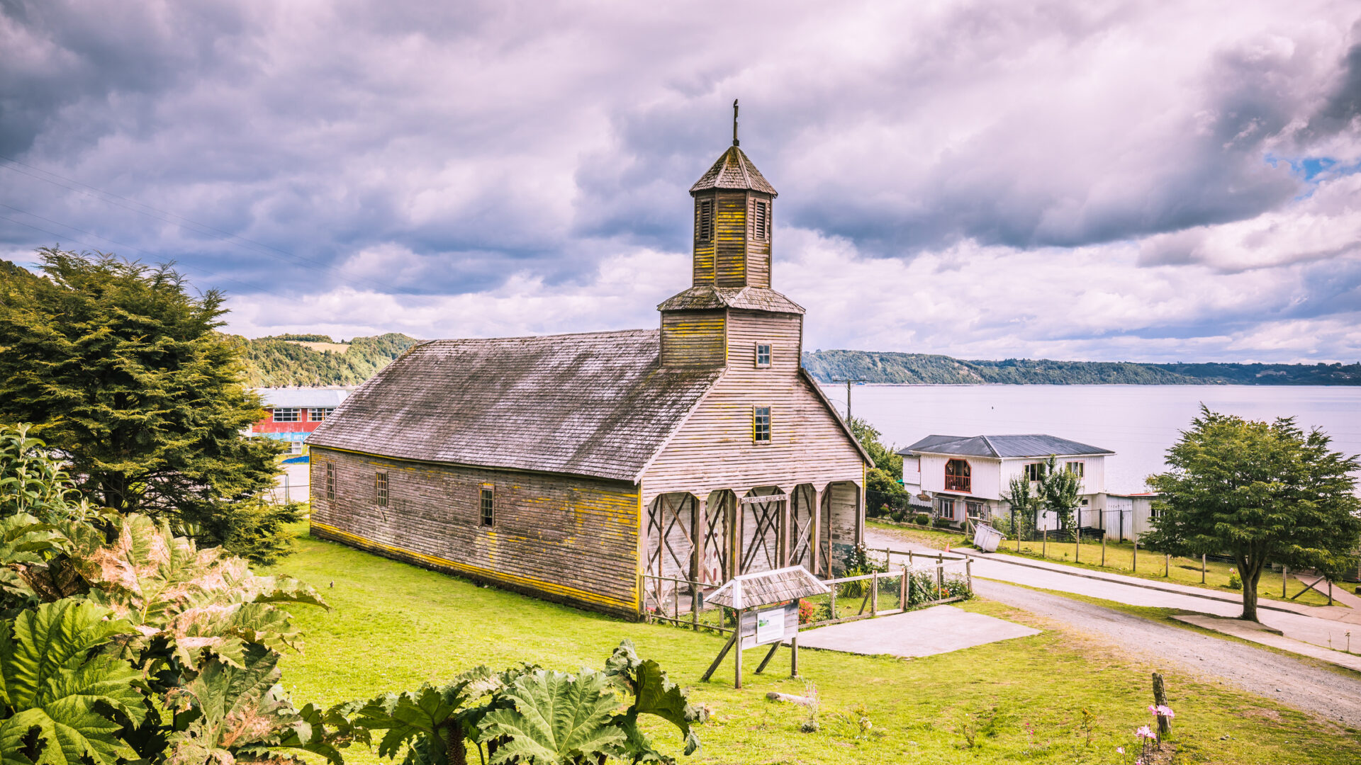 The wooden church of Santiago Apostol stands on a green meadow on the coast of Chiloe, Chile