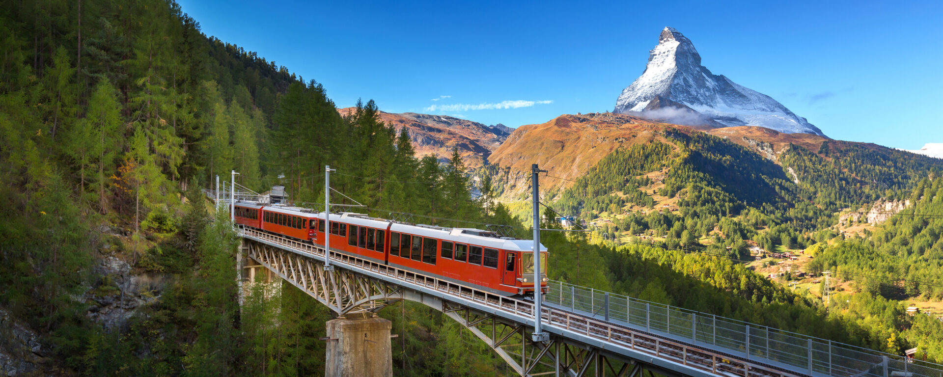 multi country trips: Gornergrat train crossing a bridge with a view of Zermatt in the background.